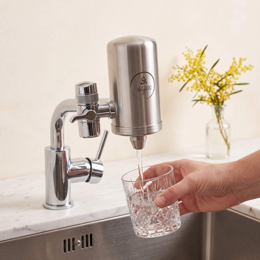 Filling a glass from the HolyH₂O Tap Mate on a kitchen tap